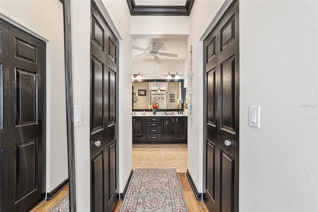 hall with sink, crown molding, and light wood-type flooring