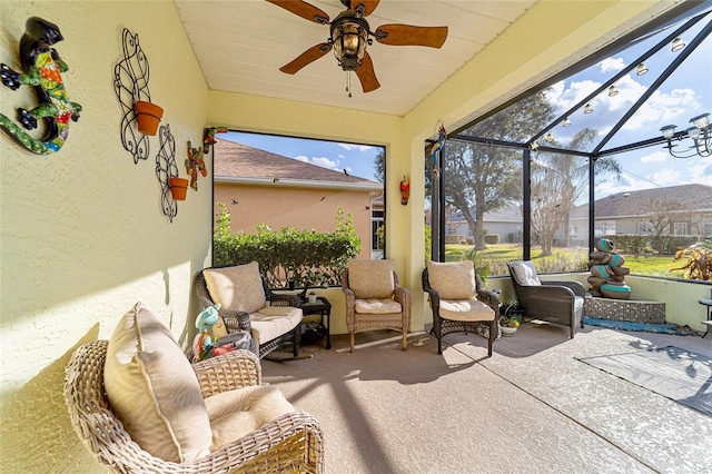 view of patio featuring ceiling fan, an outdoor living space, and glass enclosure