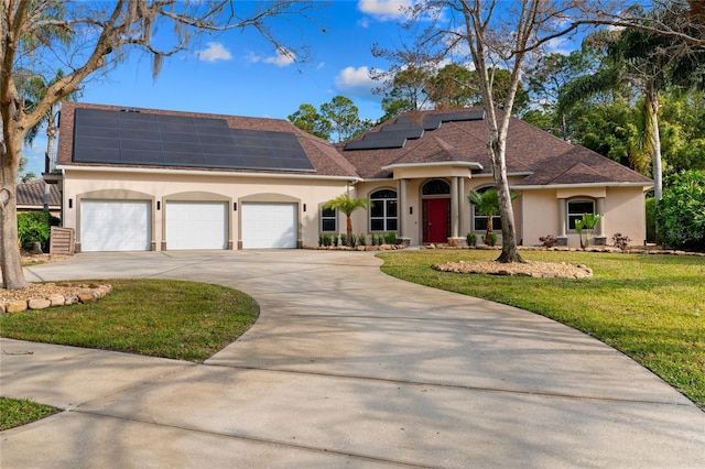 view of front facade with a garage, a front yard, and solar panels