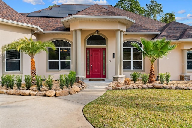 entrance to property with a yard and solar panels