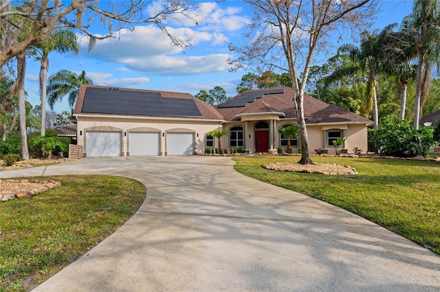 view of front of home with a garage, solar panels, and a front lawn