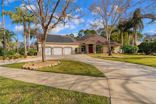 view of front of property with a garage, a front lawn, and solar panels