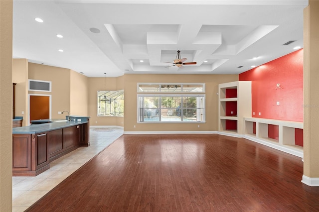 unfurnished living room with coffered ceiling, sink, light hardwood / wood-style floors, and ceiling fan