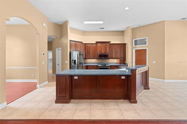 kitchen featuring appliances with stainless steel finishes, sink, backsplash, a kitchen bar, and a large island with sink