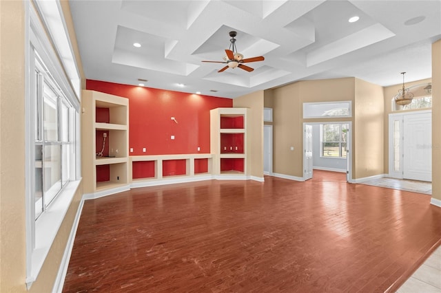 unfurnished living room featuring coffered ceiling, built in features, ceiling fan, and light wood-type flooring