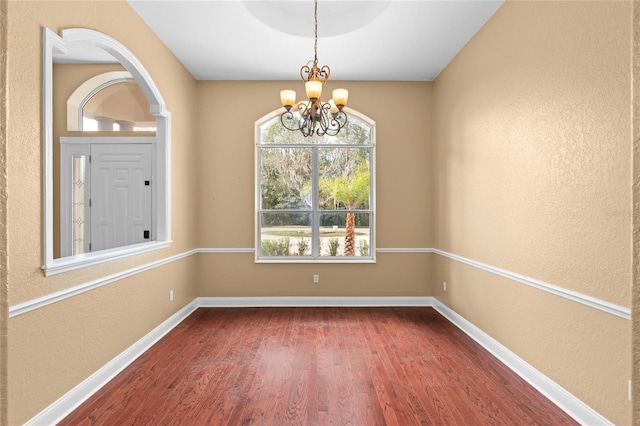 unfurnished dining area featuring dark hardwood / wood-style flooring and an inviting chandelier