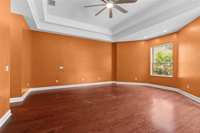 empty room with hardwood / wood-style floors, a tray ceiling, and ornamental molding