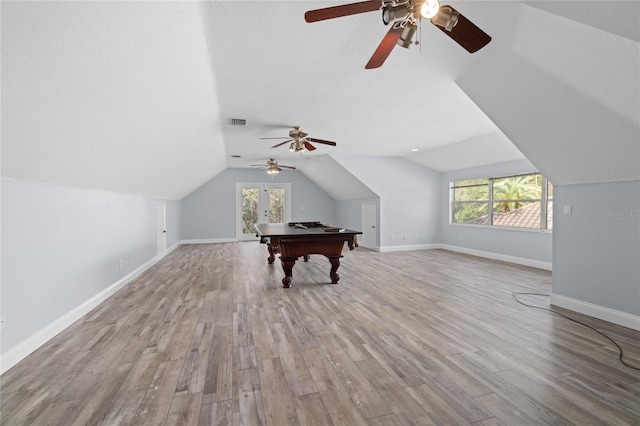 additional living space with vaulted ceiling, a wealth of natural light, a textured ceiling, and light wood-type flooring