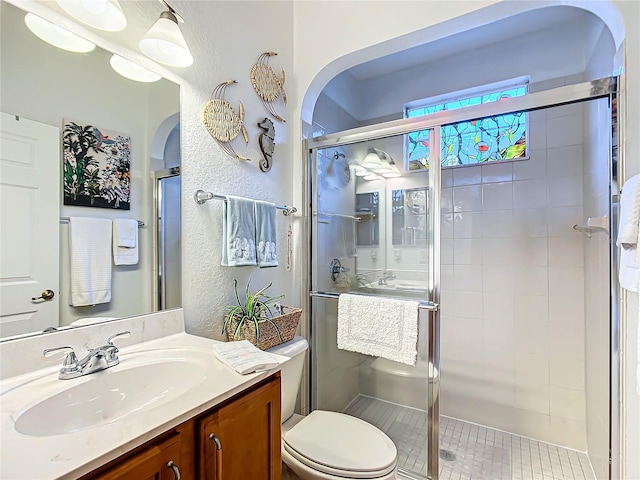 bathroom featuring vanity, toilet, and a shower with door