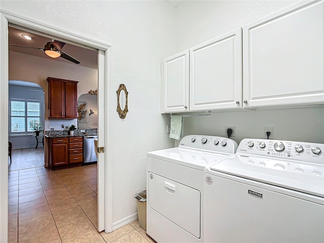 clothes washing area featuring washer and clothes dryer, cabinets, and light tile patterned flooring