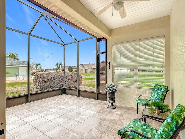 unfurnished sunroom with beamed ceiling and ceiling fan