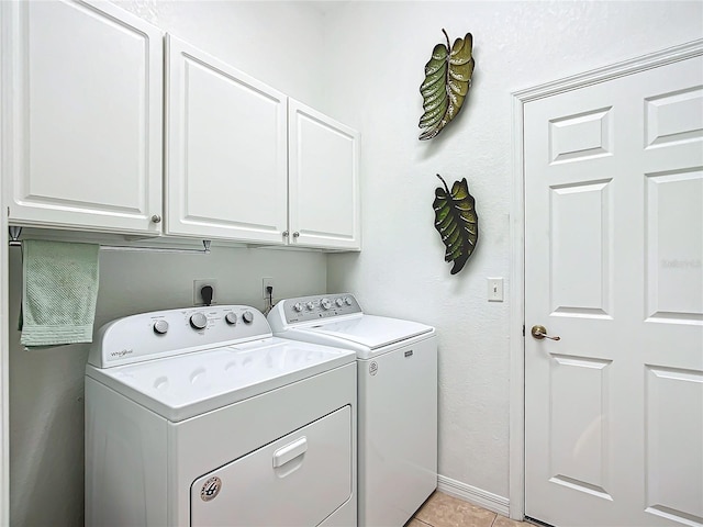 laundry room with light tile patterned floors, washer and clothes dryer, and cabinets