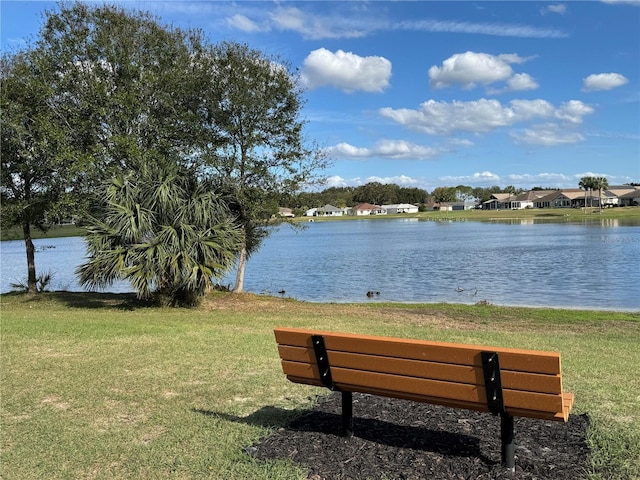 surrounding community with a water view and a lawn