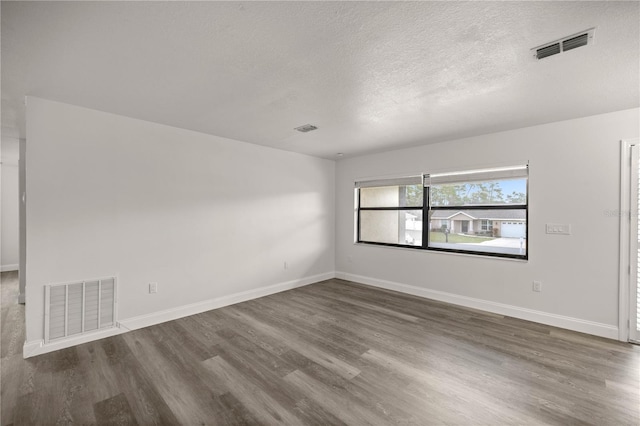 unfurnished room with a textured ceiling and dark hardwood / wood-style flooring