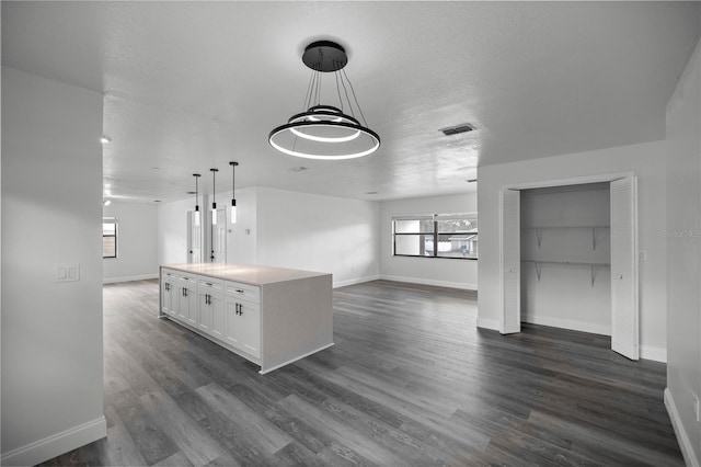 kitchen featuring white cabinetry, hanging light fixtures, a textured ceiling, dark hardwood / wood-style floors, and a kitchen island