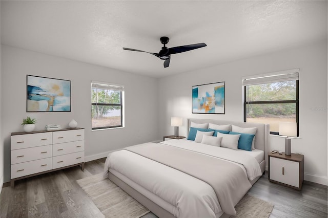 bedroom with ceiling fan, dark wood-type flooring, and a textured ceiling