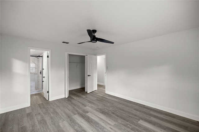 unfurnished bedroom with connected bathroom, wood-type flooring, a closet, and ceiling fan