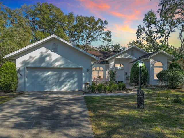 ranch-style house featuring a garage and a lawn