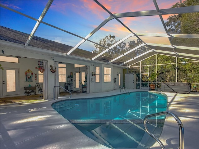 pool at dusk with a lanai and a patio