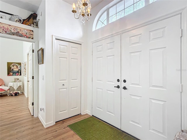 foyer with a high ceiling, a notable chandelier, and light wood-type flooring