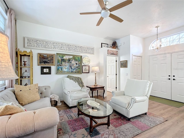 living room featuring ceiling fan with notable chandelier and hardwood / wood-style floors