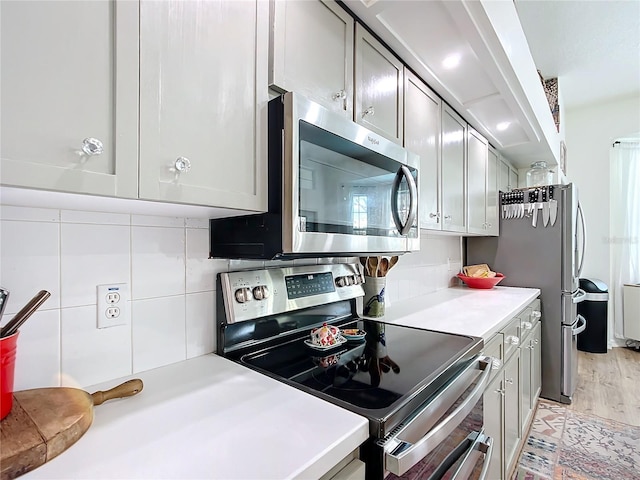 kitchen with tasteful backsplash, gray cabinetry, and appliances with stainless steel finishes