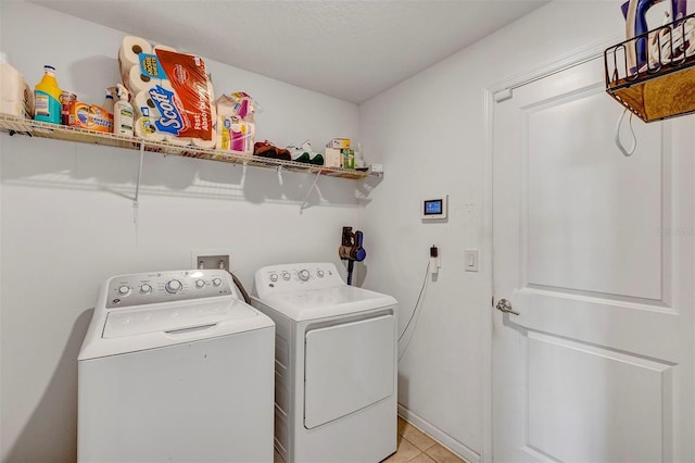 clothes washing area with washer and dryer and light tile patterned floors