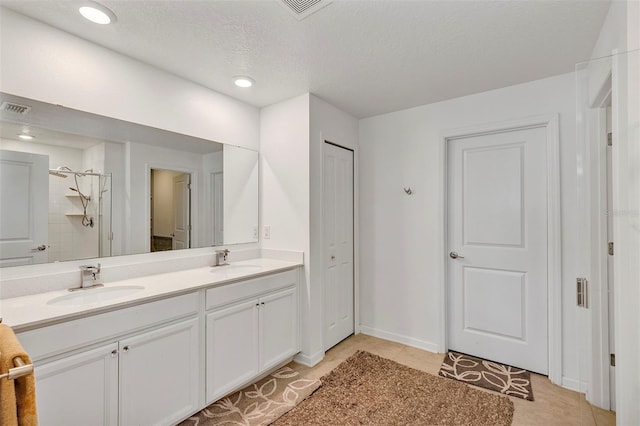 bathroom with tile patterned flooring, vanity, a textured ceiling, and walk in shower