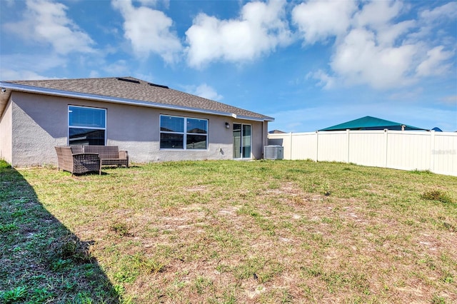 rear view of house with cooling unit and a lawn