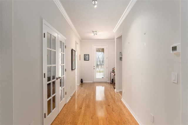 entryway with crown molding, light hardwood / wood-style flooring, french doors, and a textured ceiling