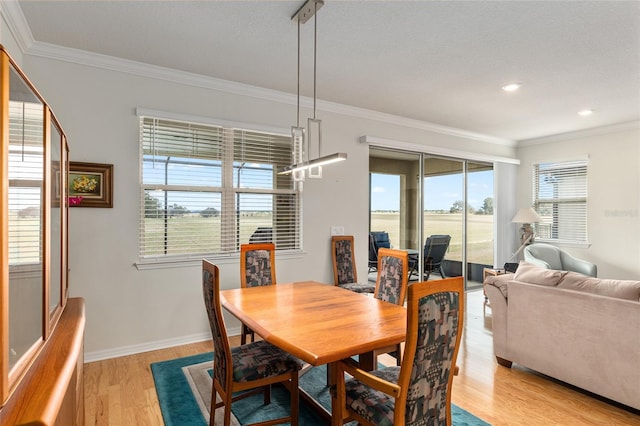 dining room with ornamental molding and light hardwood / wood-style floors