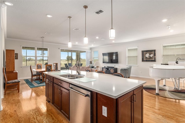 kitchen featuring sink, a kitchen island with sink, stainless steel dishwasher, and decorative light fixtures