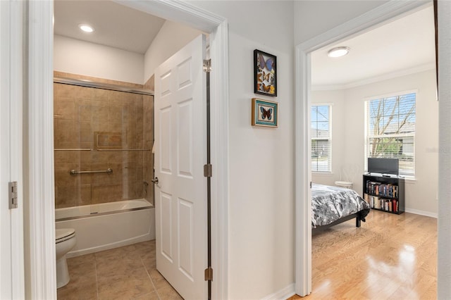 bathroom featuring ornamental molding, hardwood / wood-style floors, shower / bath combination with glass door, and toilet