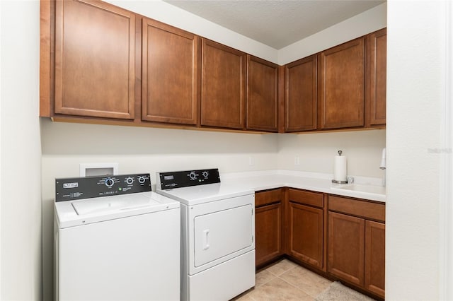 clothes washing area with sink, light tile patterned floors, cabinets, independent washer and dryer, and a textured ceiling