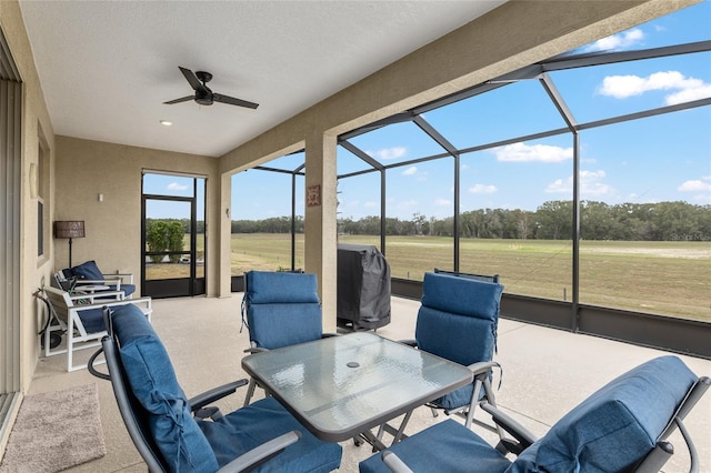 view of patio with ceiling fan, a grill, and glass enclosure