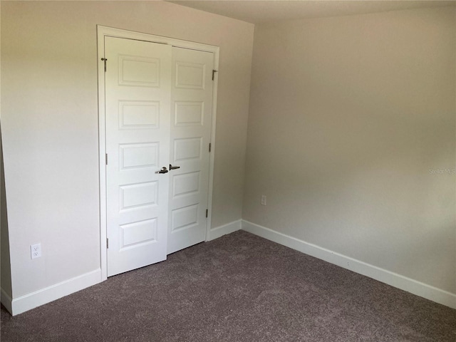 unfurnished bedroom with a closet and dark colored carpet