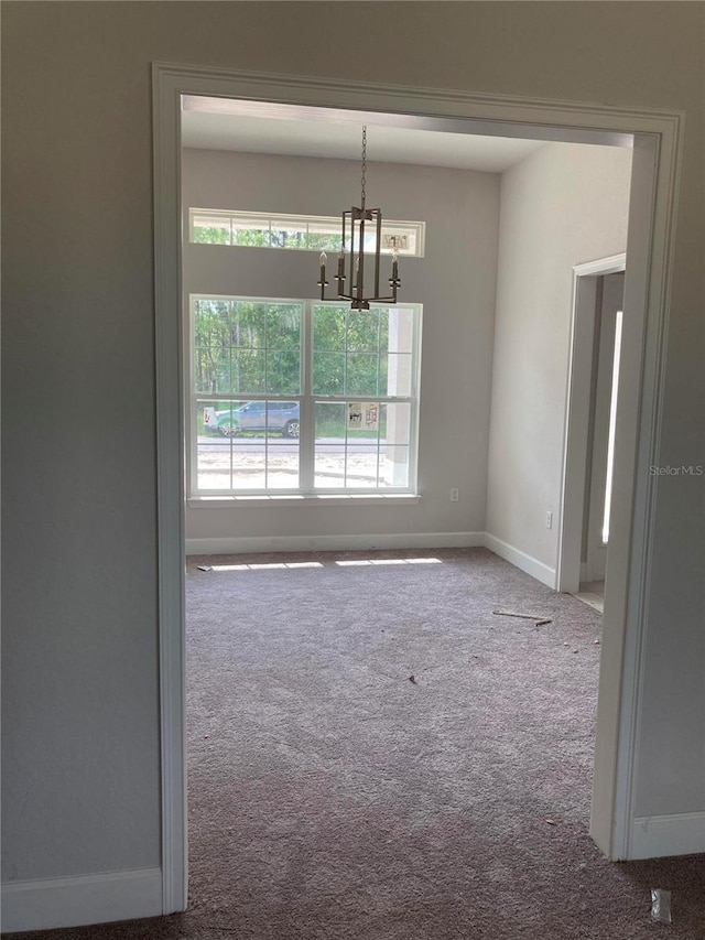 unfurnished dining area with an inviting chandelier and carpet