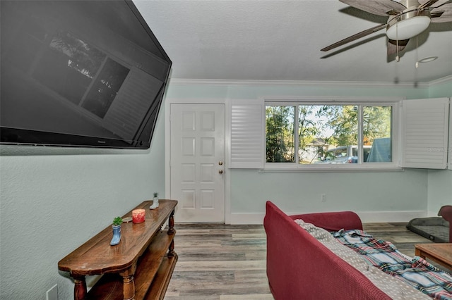 living room with crown molding, baseboards, and wood finished floors