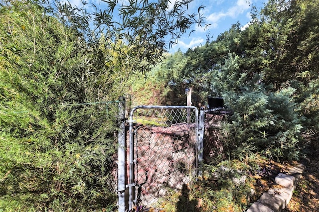 view of gate with fence and a view of trees