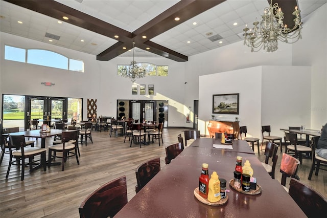 dining room featuring an inviting chandelier, a high ceiling, wood finished floors, and french doors