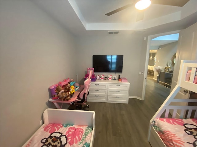 bedroom featuring ceiling fan, dark wood-style flooring, visible vents, baseboards, and a raised ceiling