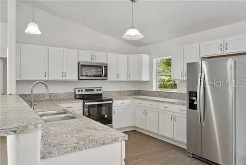 kitchen featuring appliances with stainless steel finishes, decorative light fixtures, and white cabinets