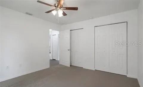 unfurnished bedroom featuring ceiling fan and two closets