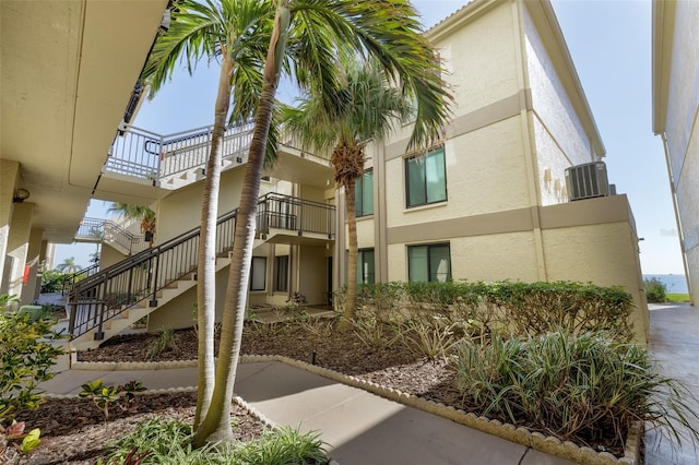 view of property featuring central air condition unit and stairs