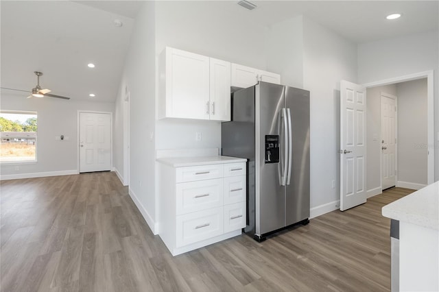 kitchen with stainless steel fridge with ice dispenser, white cabinets, ceiling fan, light hardwood / wood-style floors, and a high ceiling