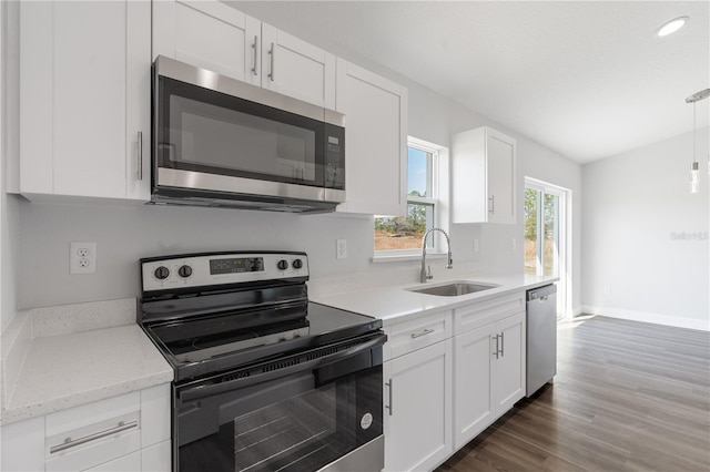 kitchen with sink, dark wood-type flooring, white cabinetry, stainless steel appliances, and vaulted ceiling