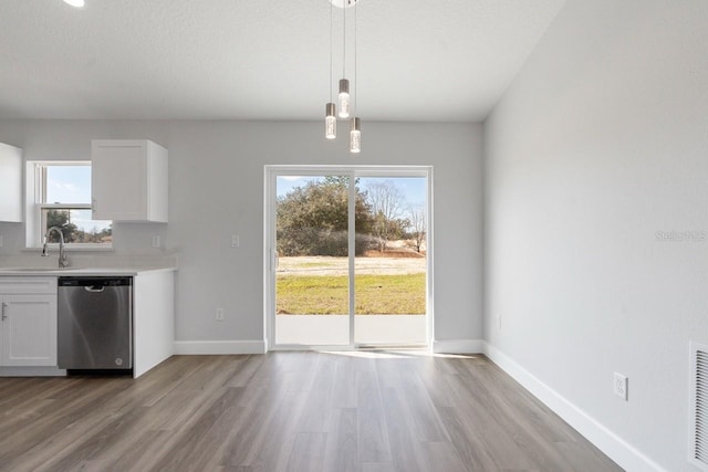 kitchen featuring decorative light fixtures, dishwasher, sink, white cabinets, and light wood-type flooring