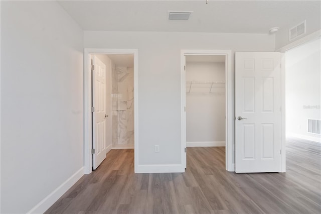 unfurnished bedroom featuring hardwood / wood-style flooring, a spacious closet, and a closet