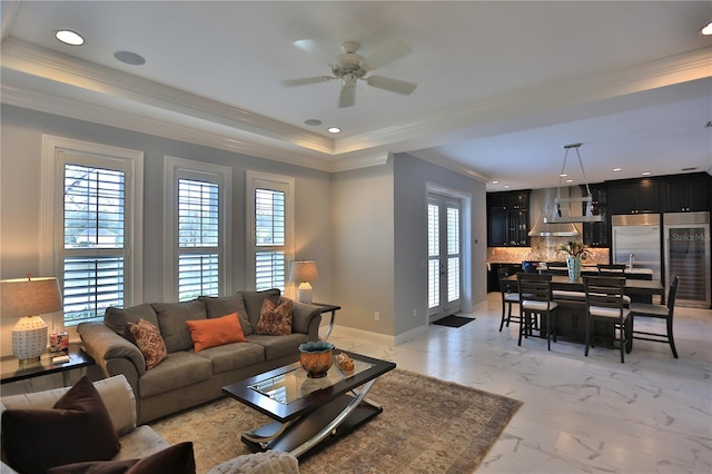 living room with ceiling fan, ornamental molding, plenty of natural light, and a tray ceiling