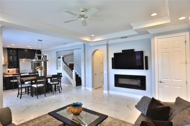 living room with a raised ceiling, ornamental molding, and ceiling fan